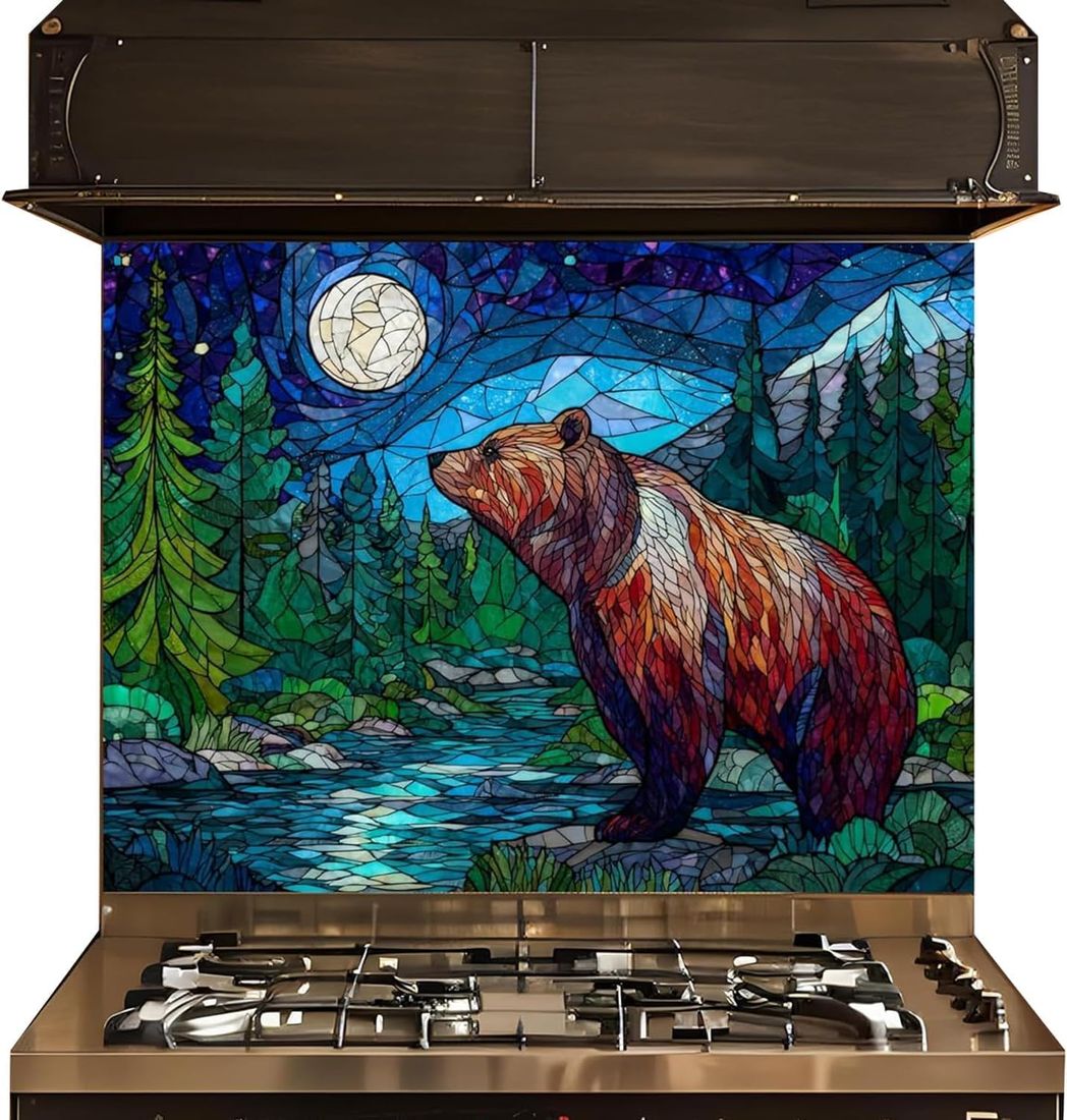 A gas range stove with a large stained-glass style backsplash featuring a brown bear under a full moon in a forest by a river.