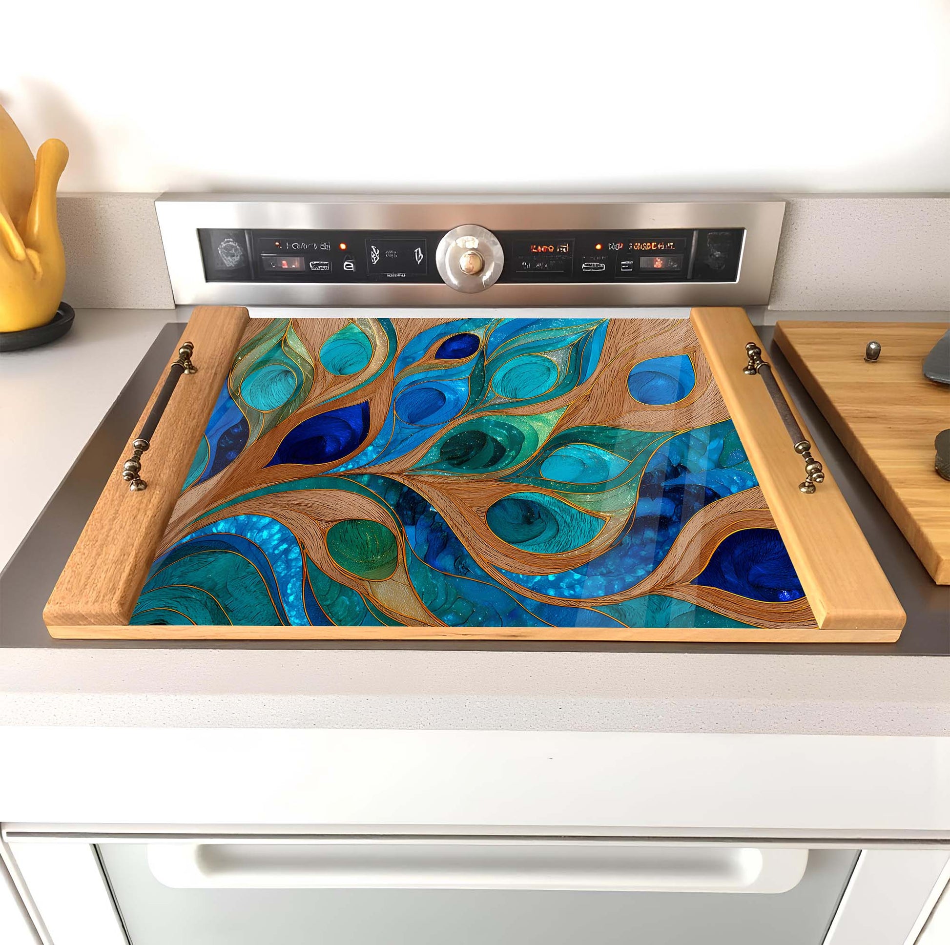 Stovetop with decorative glass panel featuring peacock feather design on a kitchen stove.
