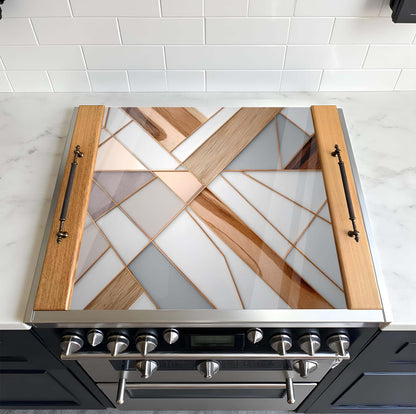 Stainless steel range hood with geometric glass design on a tiled kitchen wall.